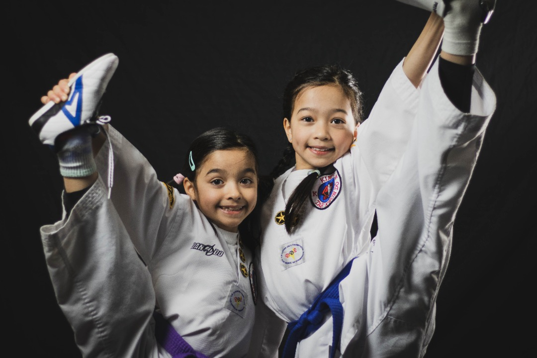 Two children doing a Taekwondo kick in Kim's Taekwondo center in Montreal