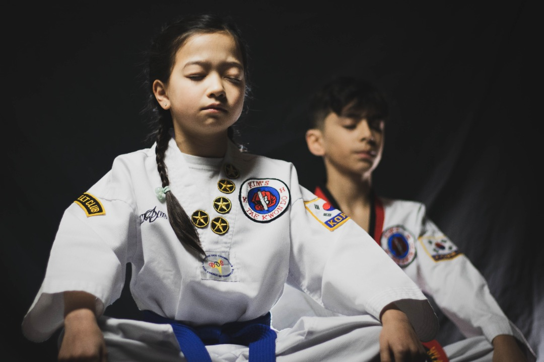 Two children doing a Taekwondo meditation in Kim's Taekwondo center in Montreal